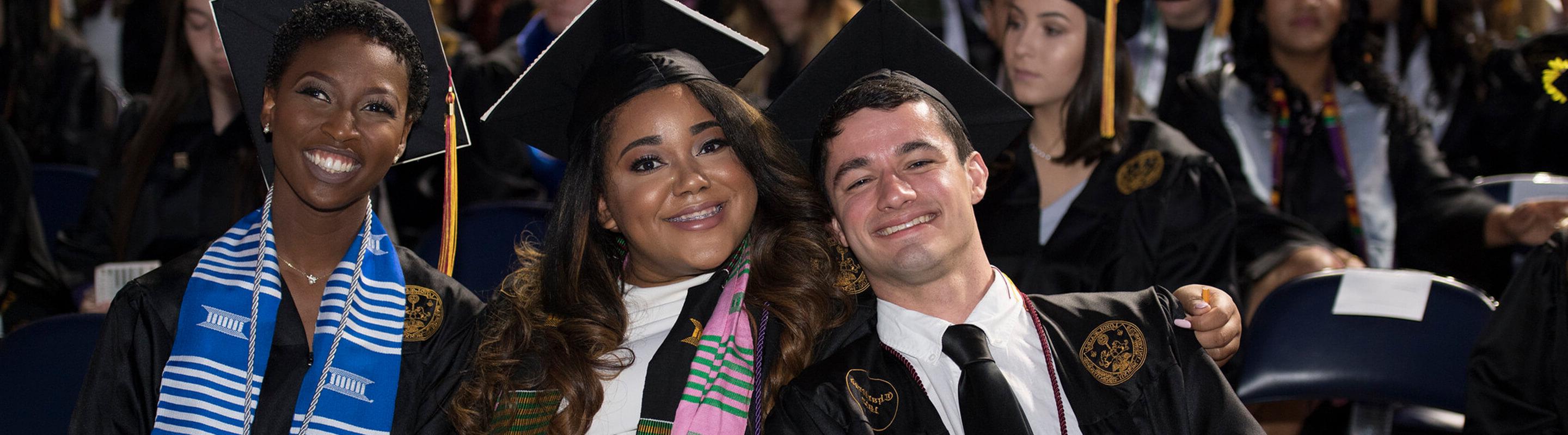 Three students in regalia sitting at commencement